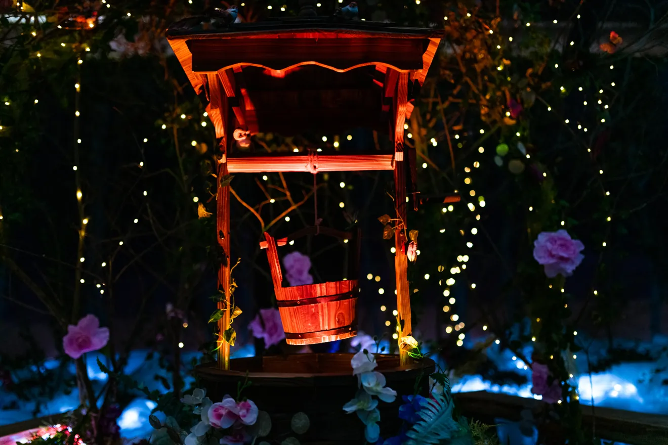 A glowing red wishing well among twinkling lights and flowers